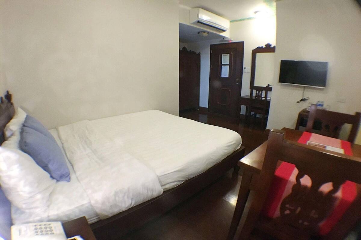 Un dormitorio con cama, escritorio, silla, televisor y armario.
