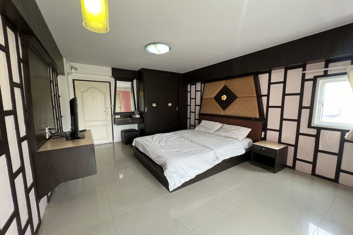 Une chambre à coucher avec un lit, des tables de chevet, une commode et une fenêtre.