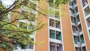A multi-story building with a mix of brick and white exterior walls, air conditioning units on the windows, and a sign indicating a business or service on the ground floor. - Phongsathon Mansion (Bangkok)