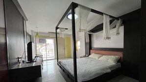A bedroom with a four-poster bed, a desk with a computer, and a view of the outside. - Phongsathon Mansion (Bangkok)