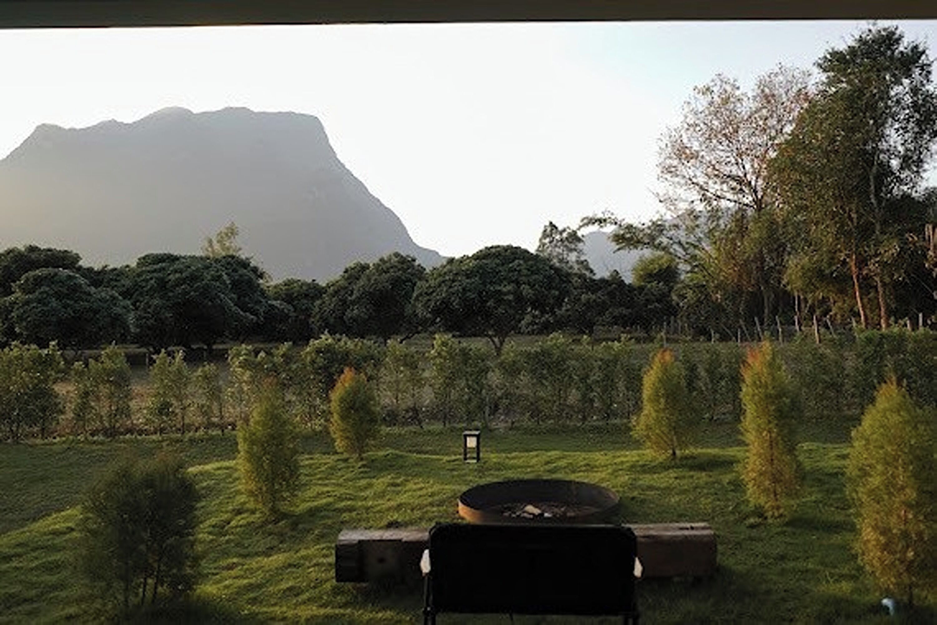 Uma área ao ar livre com gramado, uma lareira, bancos e um candeeiro.