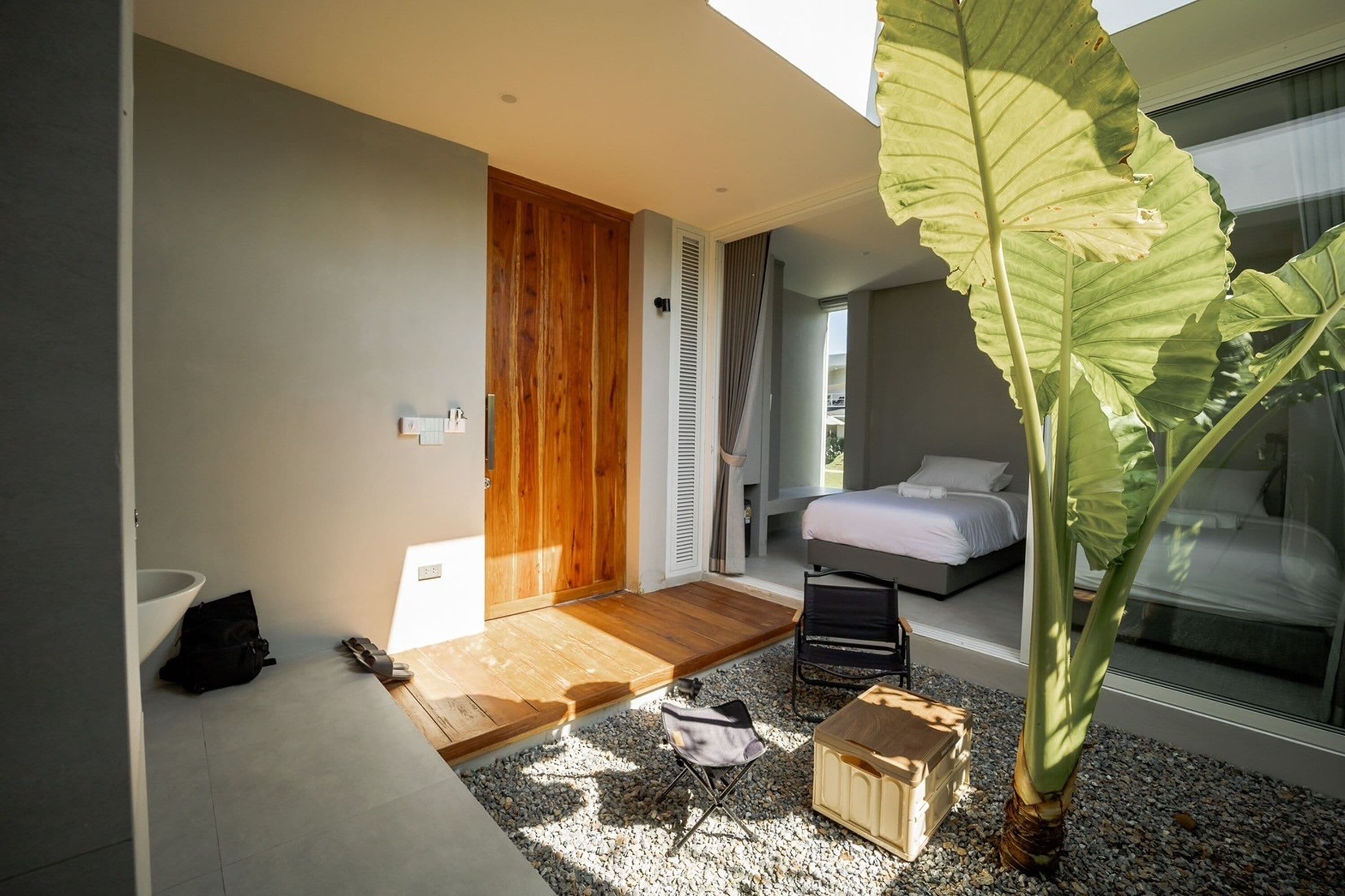 A modern bedroom with a large window, a wooden door, and a plant.