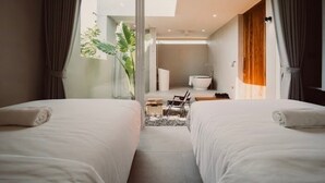 Una habitación de hotel moderna con dos camas, un baño y vistas al exterior.