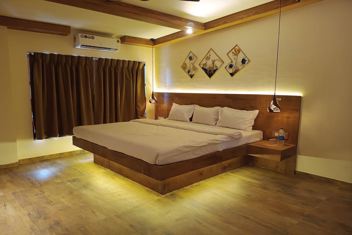 A bedroom with a large bed, wooden headboard, bedside tables, and a wall-mounted air conditioner.
