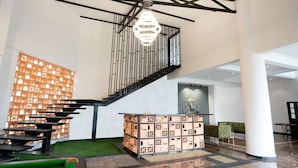 Un interior moderno con una escalera, una mesa de recepción y una pared decorativa.