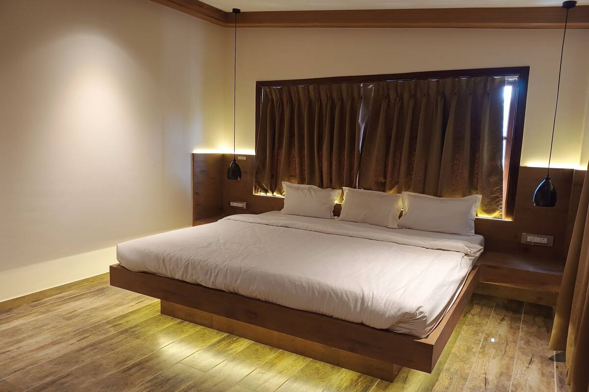A modern bedroom with a large bed, wooden headboard, and bedside lamps.