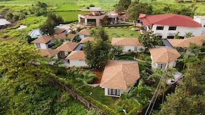 Un barrio residencial con varias casas, algunas con tejados rojos y otras con tejas marrones, rodeado de abundante vegetación y campos.