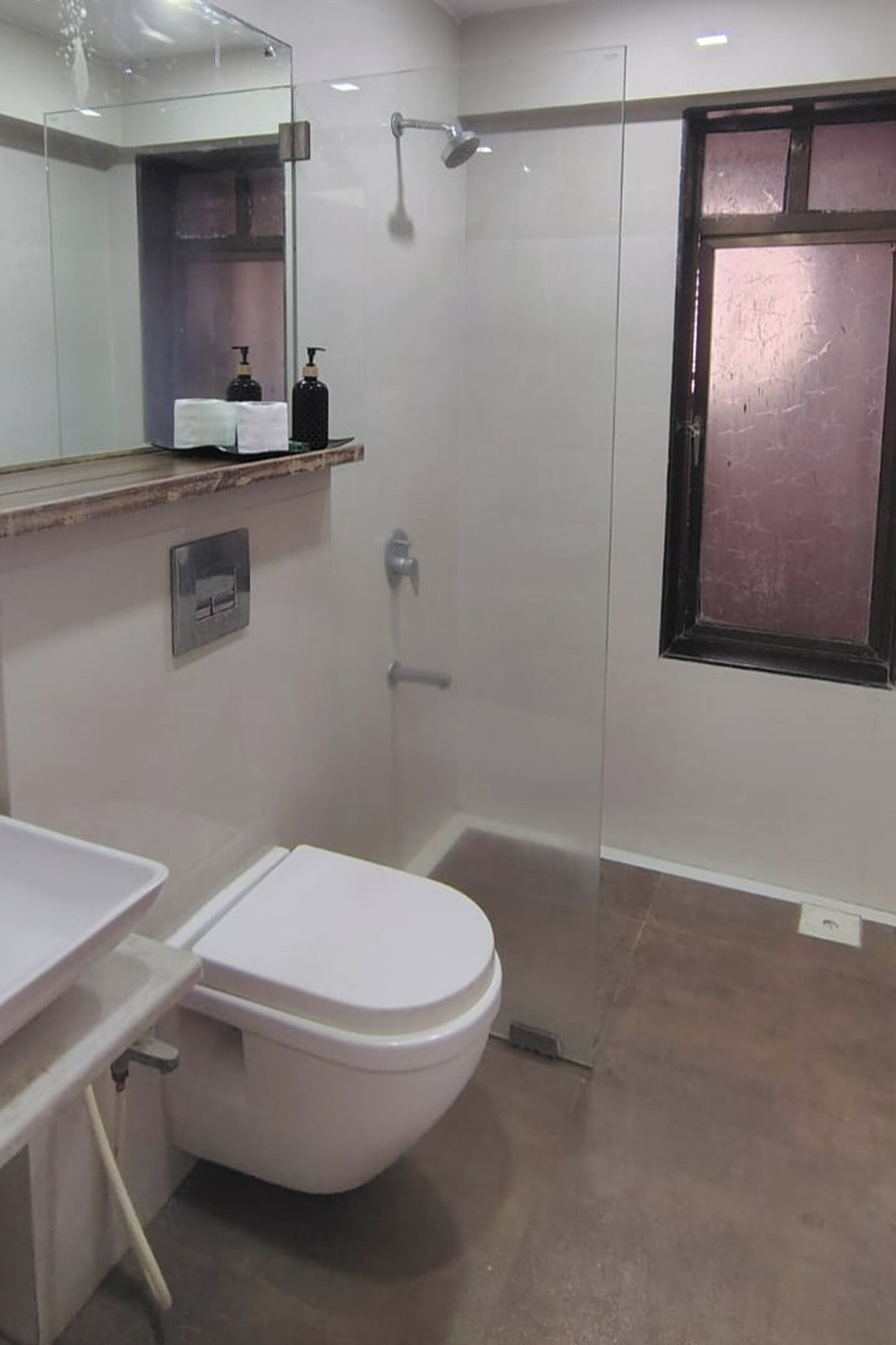 A bathroom with a toilet, a shower, a sink, and a mirror.