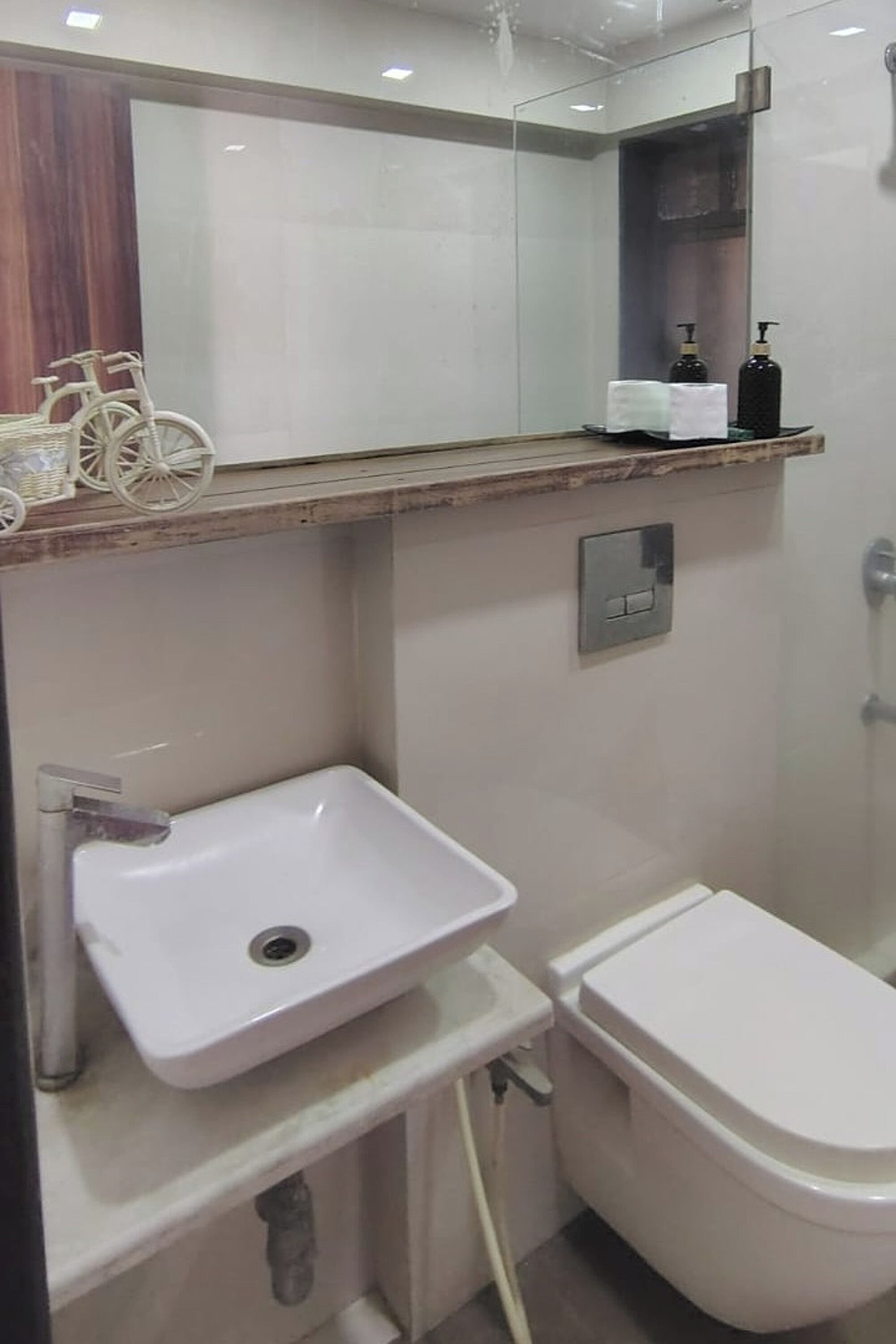 Un baño con lavamanos blanco, inodoro y espejo sobre el lavamanos.