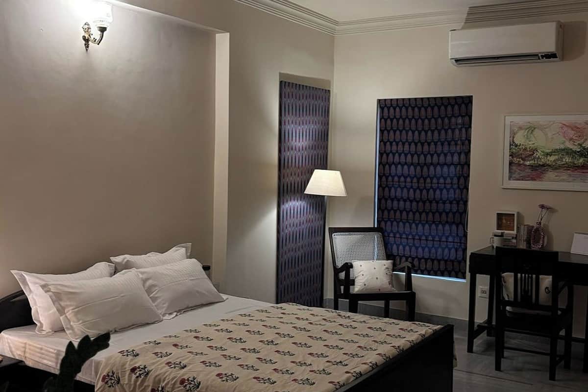 Ein Schlafzimmer mit Bett, Deckenventilator, Lampe, Sessel, Tisch und einer Topfpflanze.