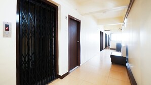 A hallway with a black metal gate, a brown door, and a white wall with a number sign. - Hotel Della Comfort near Ambreshwar Shiv Mandir, Ambernath (Ambernath)