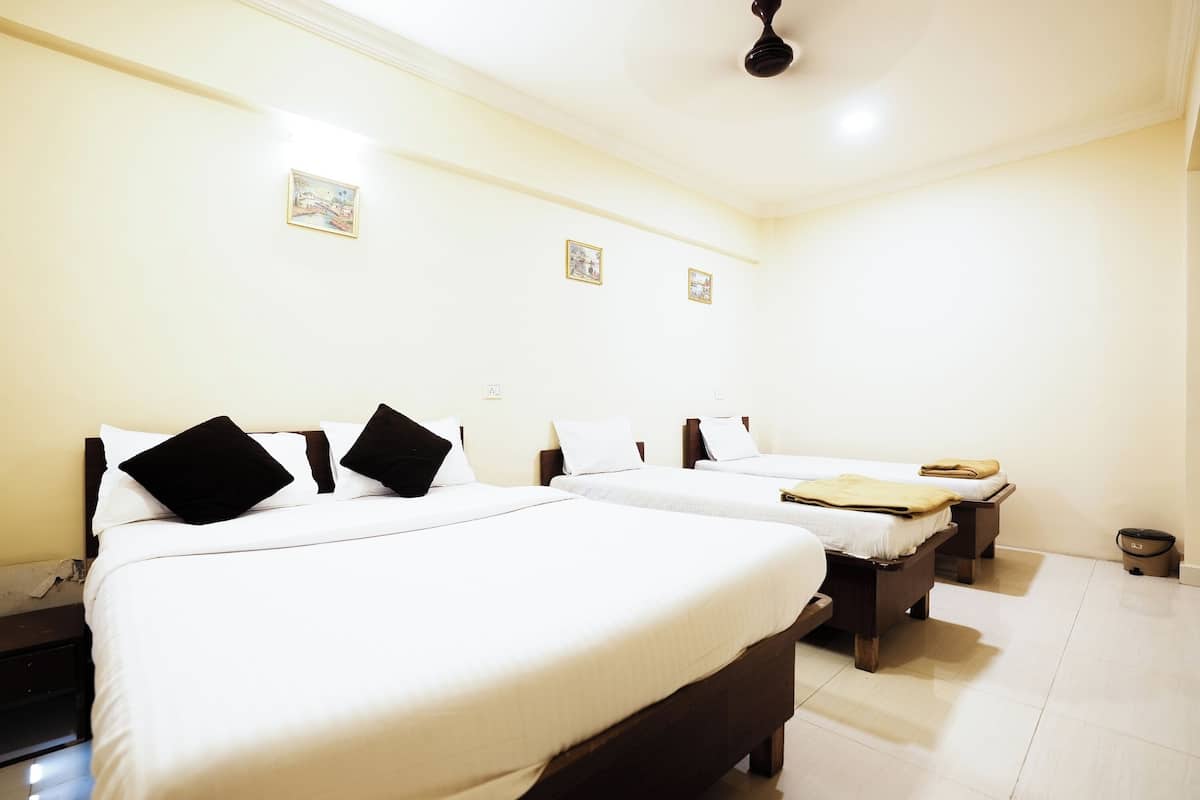 Habitación de hotel con dos camas, ropa de cama blanca y un ventilador de techo.