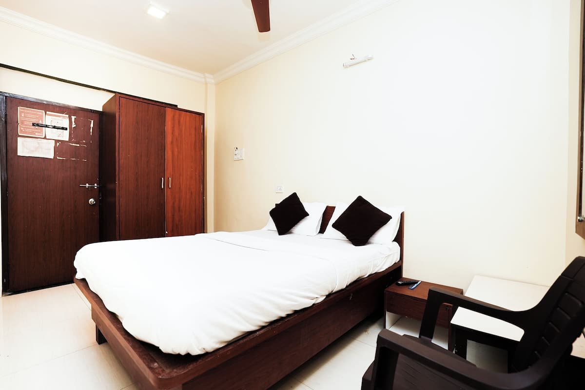 Un dormitorio con una cama individual, un armario de madera, un escritorio con silla y una mesita.