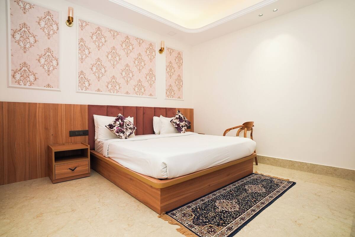 Un dormitorio con cama de madera, una mesita de noche, una alfombra estampada y paneles decorativos en la pared.