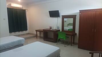 Habitación de hotel con dos camas, un escritorio, una silla, un televisor, un armario y un equipo de aire acondicionado.