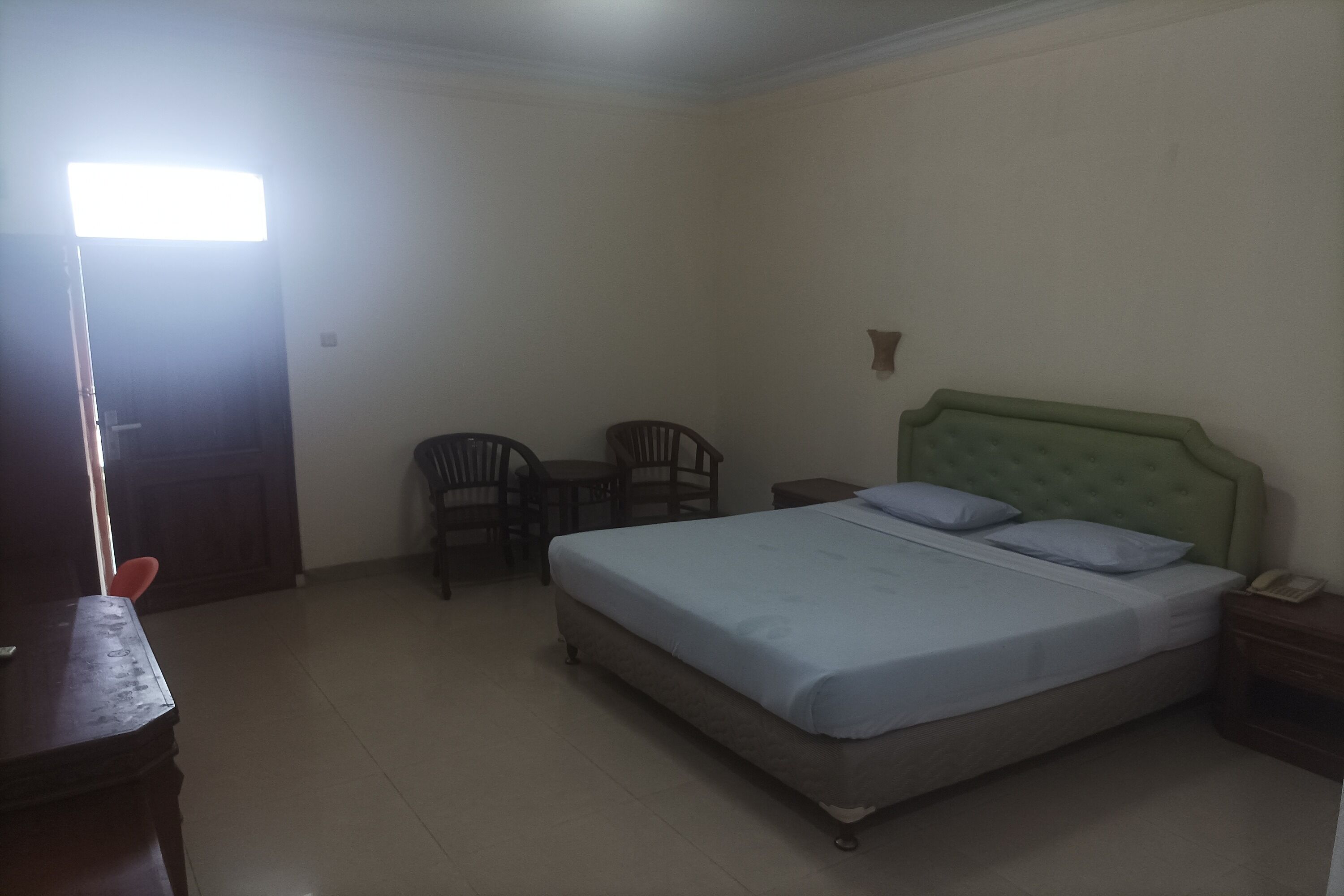 Un dormitorio con cama, escritorio, dos sillas y mesita de noche.