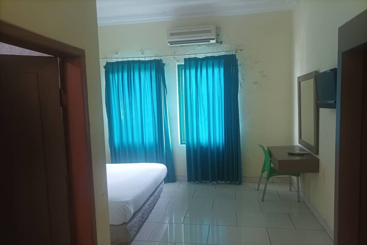 Une chambre avec un lit, un bureau, une chaise et un téléviseur.