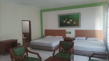 Una habitación de hotel con dos camas, un escritorio de madera, una silla y un cuadro en la pared.