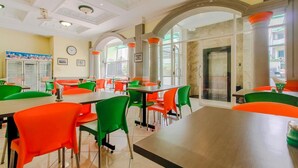 A dining area with tables and chairs, large windows, and a clock on the wall. - Permata Hijau (North Cirebon)