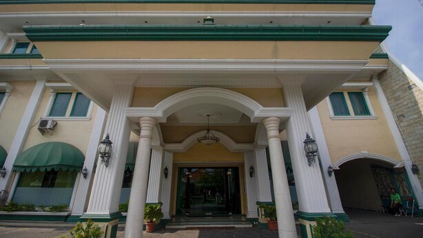 A building with a grand entrance featuring a central archway, flanked by columns, and a green and white color scheme. - Permata Hijau (North Cirebon)