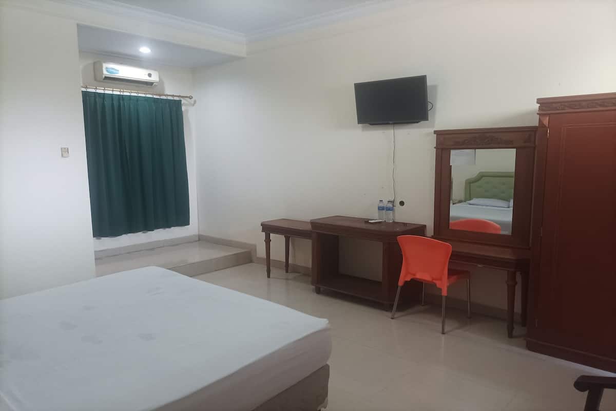 Une chambre d’hôtel équipée d’un lit, d’un bureau, d’une chaise, d’un téléviseur fixé au mur et d’une armoire.