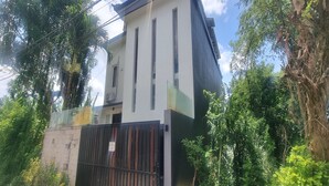 A modern building with a flat roof, surrounded by lush greenery and a gated entrance. - Tresna Villa 7 (Nusa Dua)