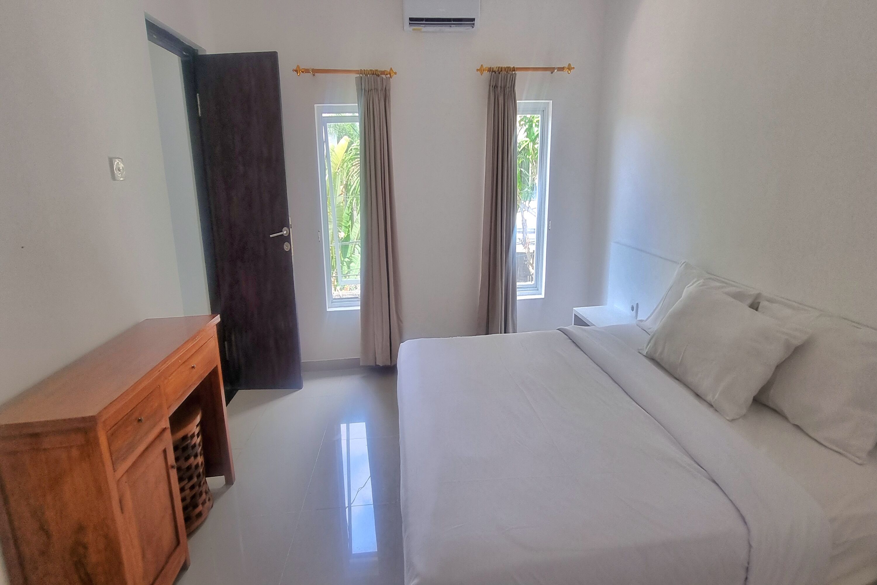 A bedroom with a bed, a wooden cabinet, and a door.