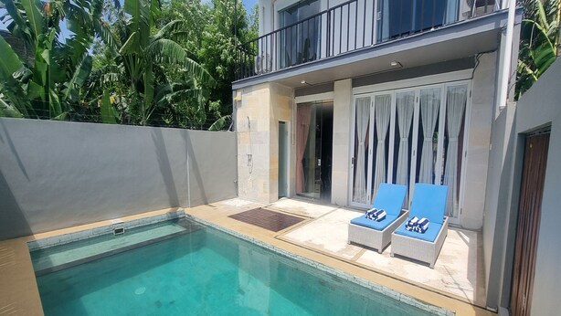 A modern pool area with clear water, two lounge chairs, and a covered patio with curtains. - Tresna Villa 7 (Nusa Dua)