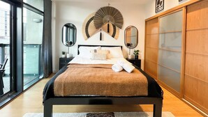A modern bedroom with a large bed, a fan, and a sliding door closet. - Hydro Apartments (Glasgow)
