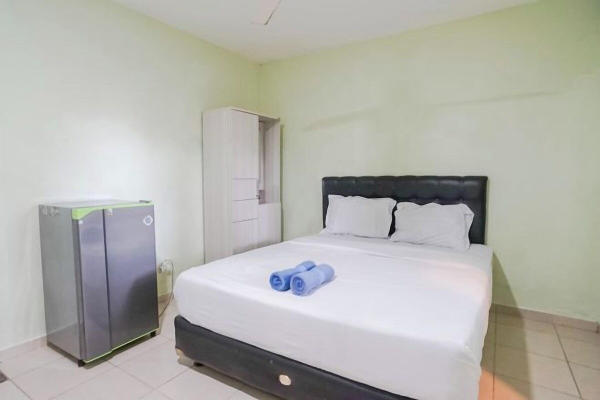 A hotel room with a bed, a wardrobe, and a small refrigerator.