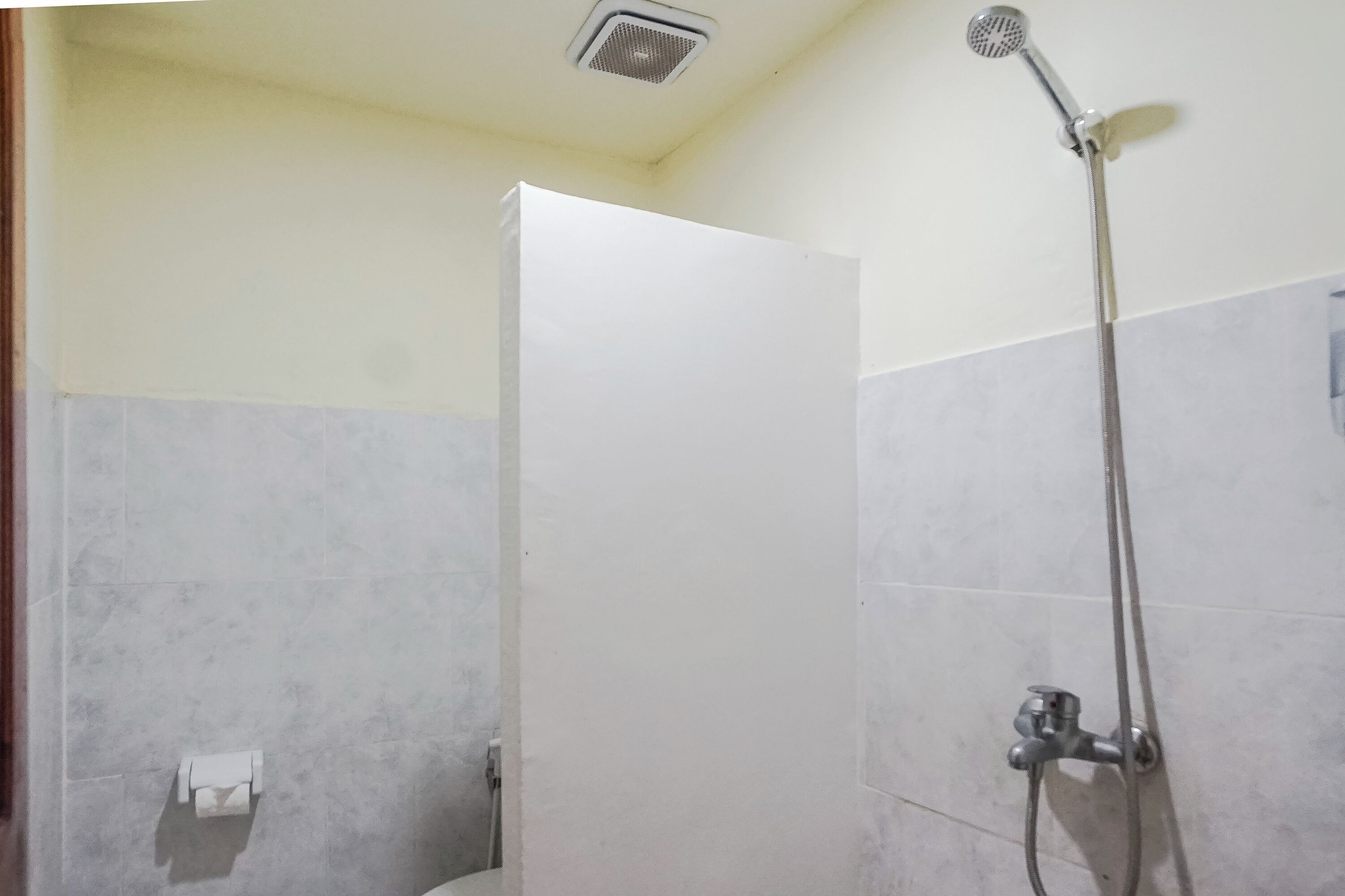 A shower area with a handheld showerhead and a wall-mounted faucet.