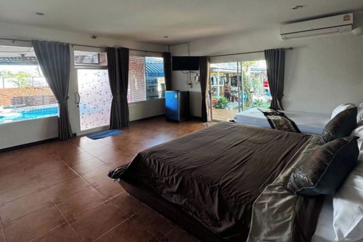 A bedroom with a bed, a TV, and a sliding door to a balcony.