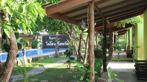 Un espacio exterior cubierto con piscina, plantas en macetas y un cartel en idioma extranjero.