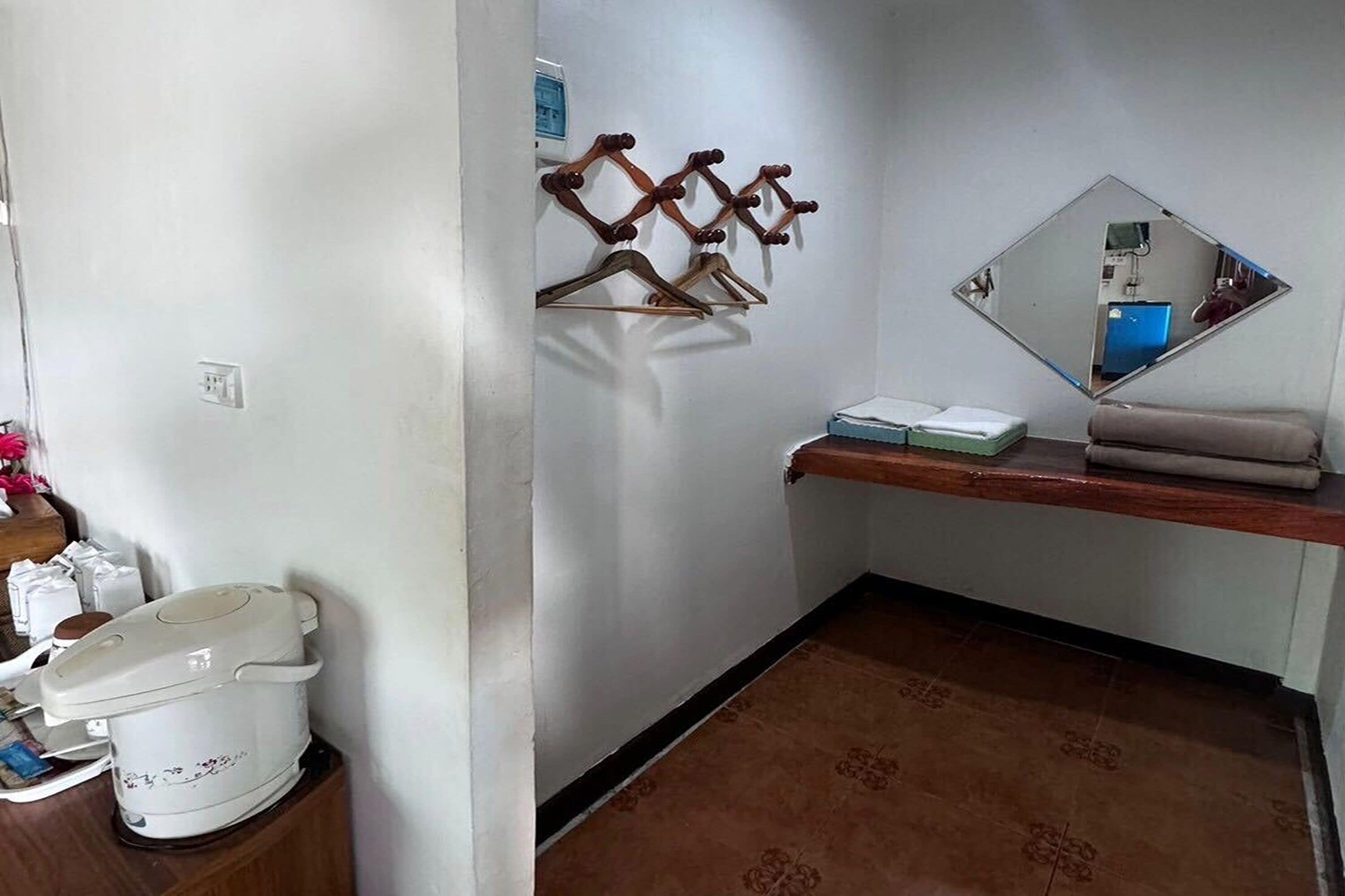 A bathroom with a white toilet, a sink with a mirror, and a wooden shelf with a towel.