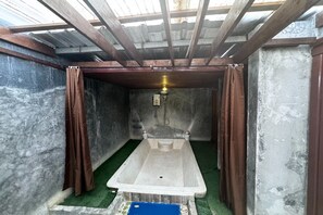 Uma casa de banho pequena e fechada com banheira, chuveiro e luminária.