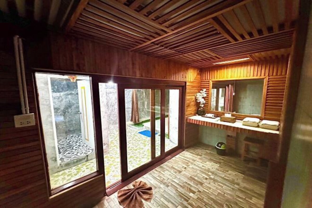 A wooden interior with a sliding glass door, a small sink area, and a mirror.