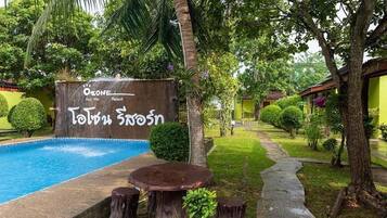 Un resort con piscina, un cartel con texto y abundante vegetación.