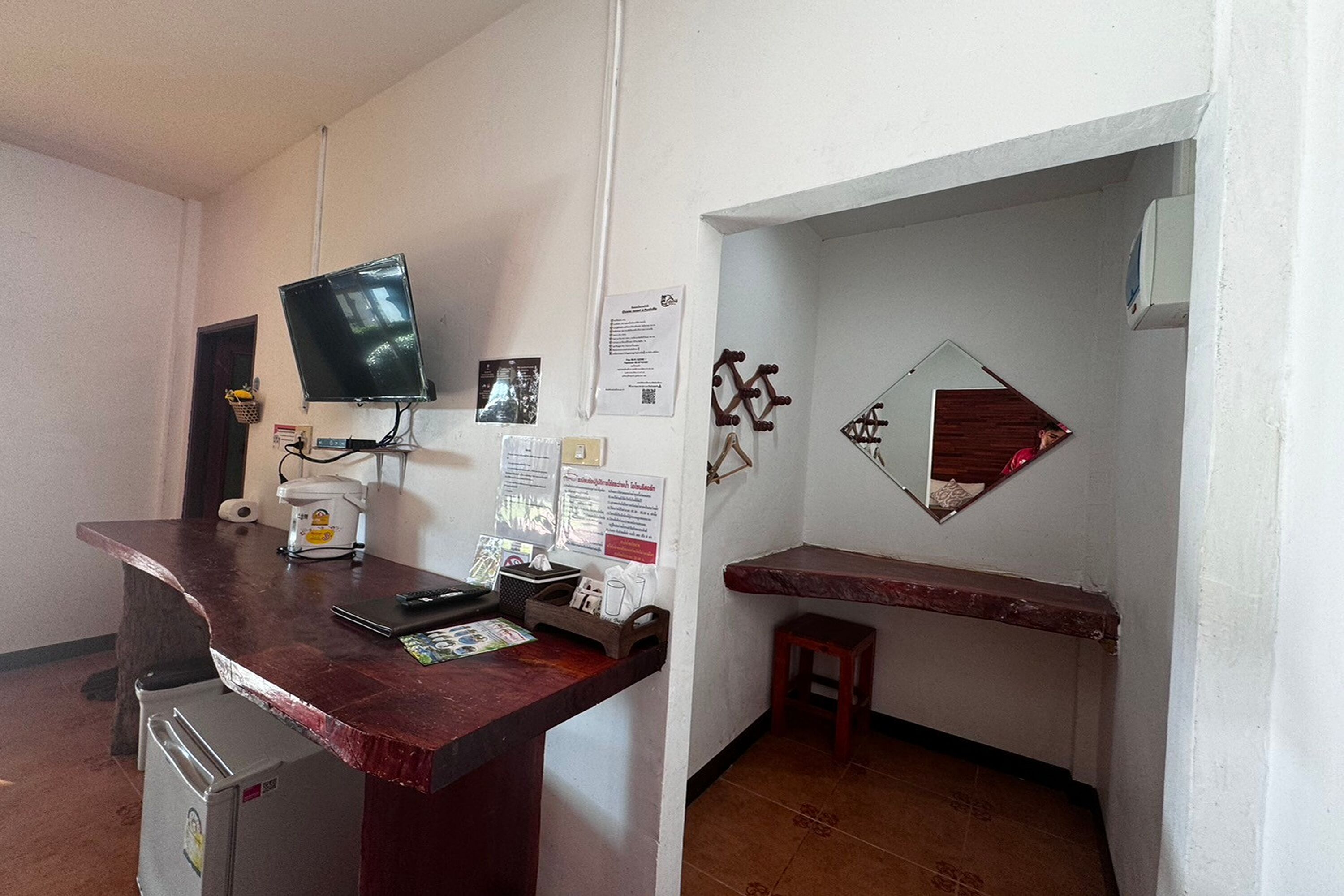 Une petite cuisine équipée d’un réfrigérateur, d’un four à micro-ondes et d’une machine à café. Un téléviseur à écran plat est fixé au mur, et il y a un petit tabouret en bois.