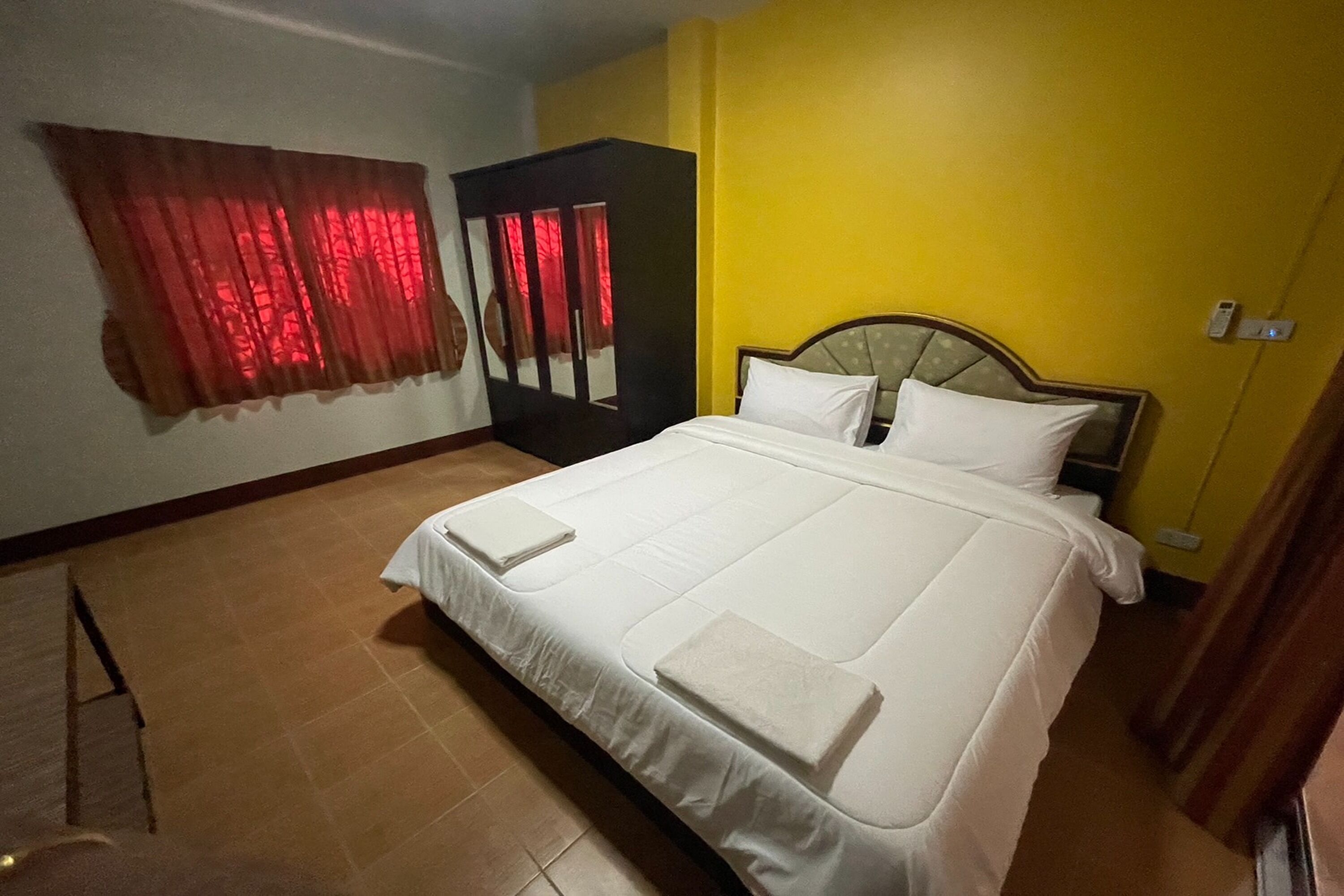A hotel room with a large bed, a wardrobe, and a mirror.