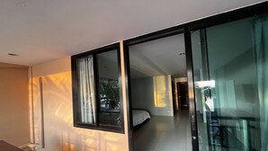 Een moderne hotelkamer met een grote schuifglazen deur naar een balkon, een bed en een klein tafeltje.