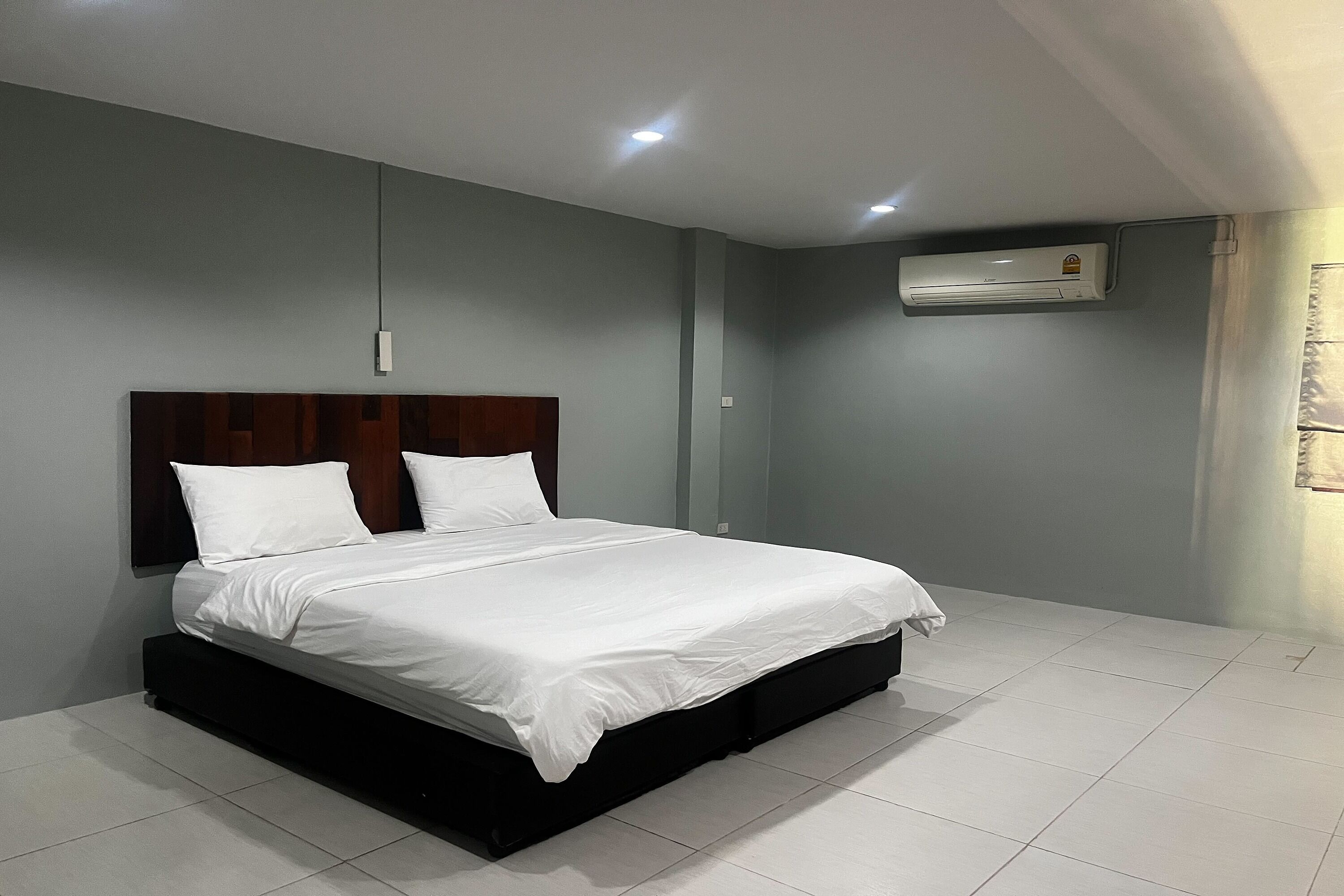 Un dormitorio moderno con una cama grande, cabecera de madera y unidad de aire acondicionado en la pared.