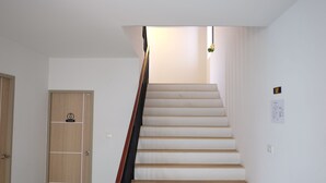 A staircase with wooden steps and a handrail, leading to a landing with a light fixture. - Prix Hotel (Chiang Mai)
