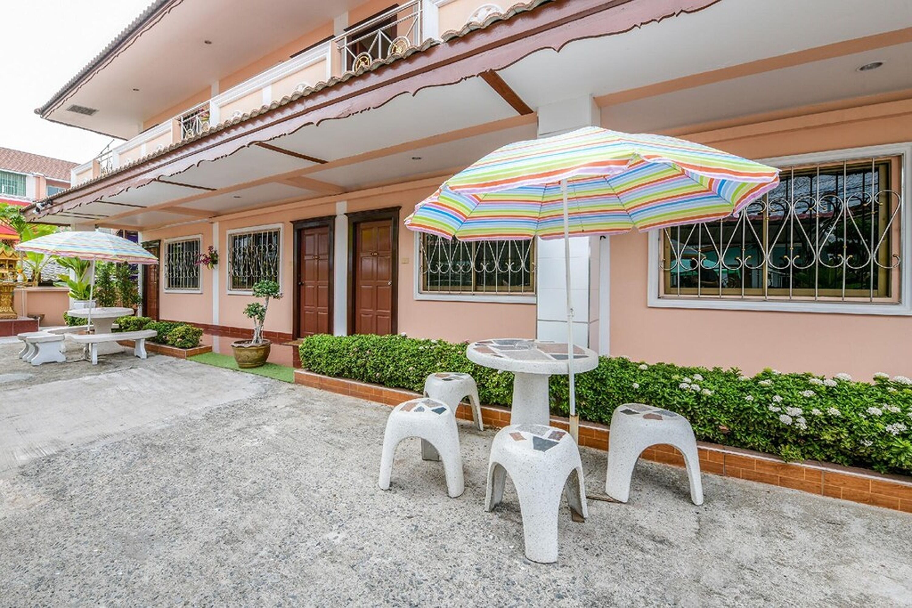 A building with a balcony, outdoor seating, and a striped umbrella.