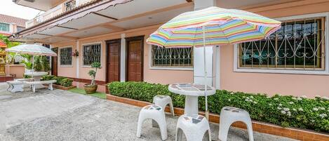 A building with a balcony, outdoor seating, and a striped umbrella.
