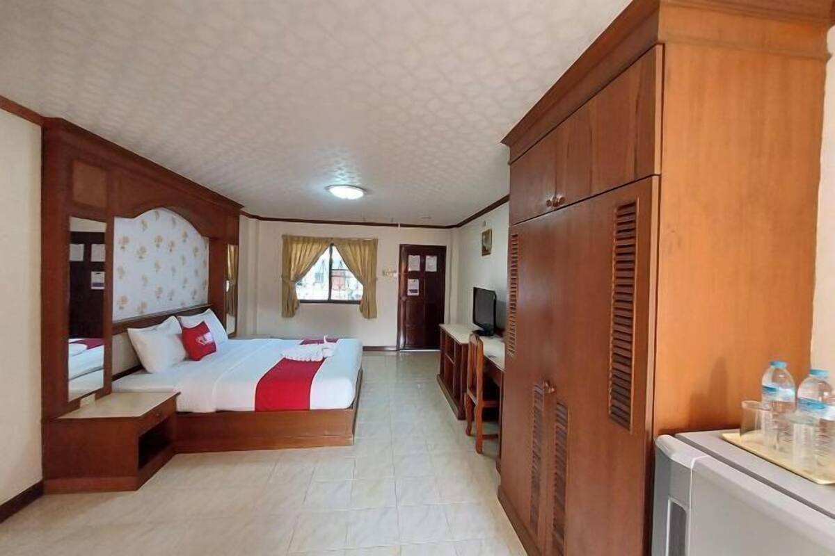 Une chambre d’hôtel équipée d’un lit, d’une télévision, d’une armoire et d’un bureau avec une chaise.
