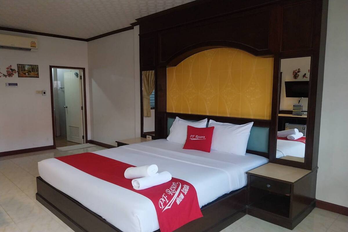 Une chambre d’hôtel avec un grand lit, une table de chevet, un miroir et une vue sur le couloir.