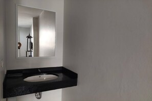 A bathroom with a black countertop, a white sink, and a rectangular mirror. - The Sculpture (Chiang Mai)
