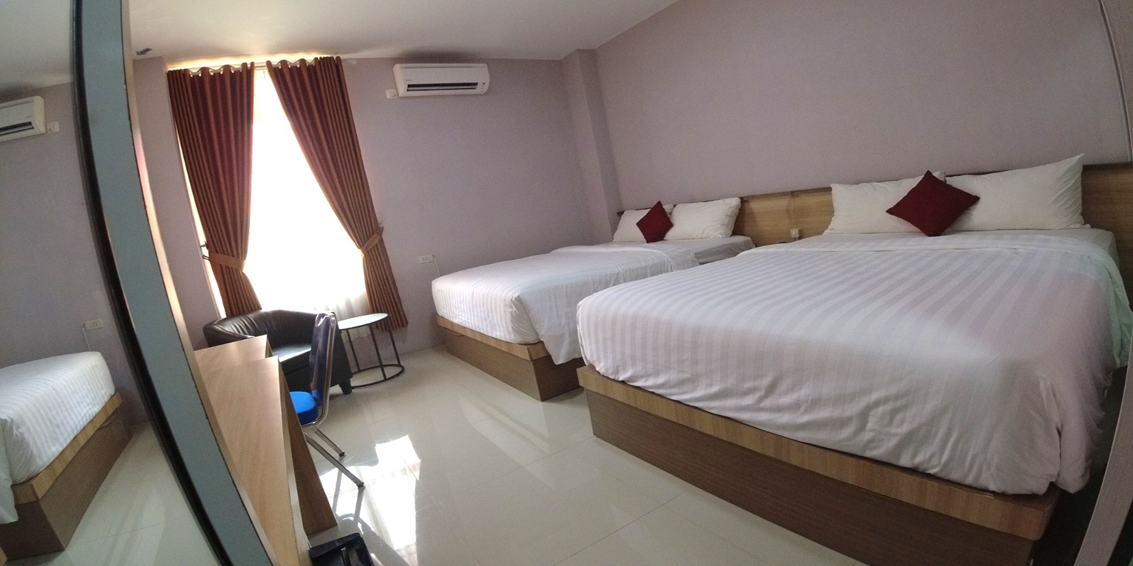 Une chambre d’hôtel avec deux lits simples, un bureau, une chaise et un miroir.