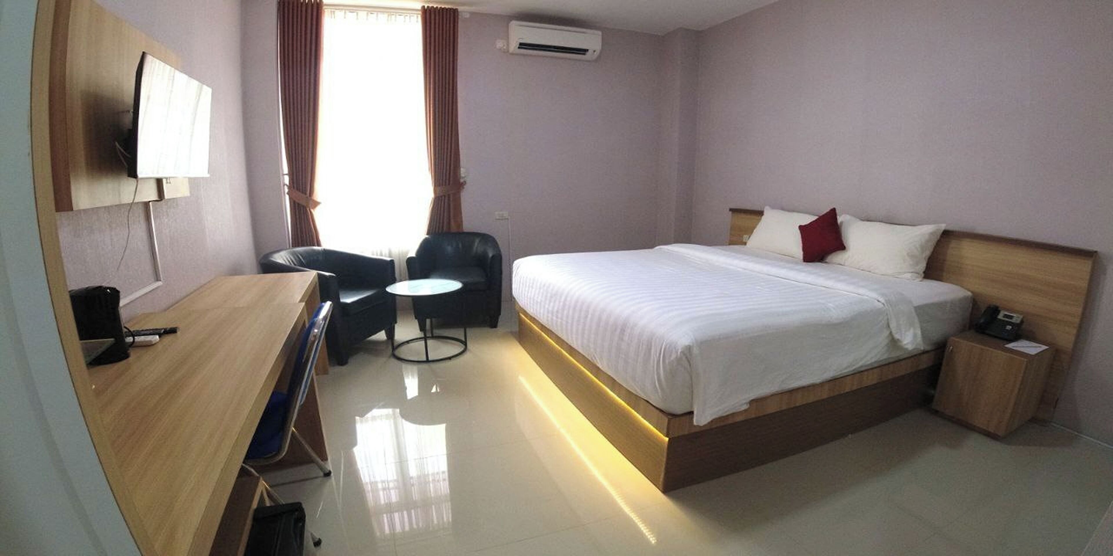 Une chambre d’hôtel avec un lit, un bureau, une chaise et une petite table.