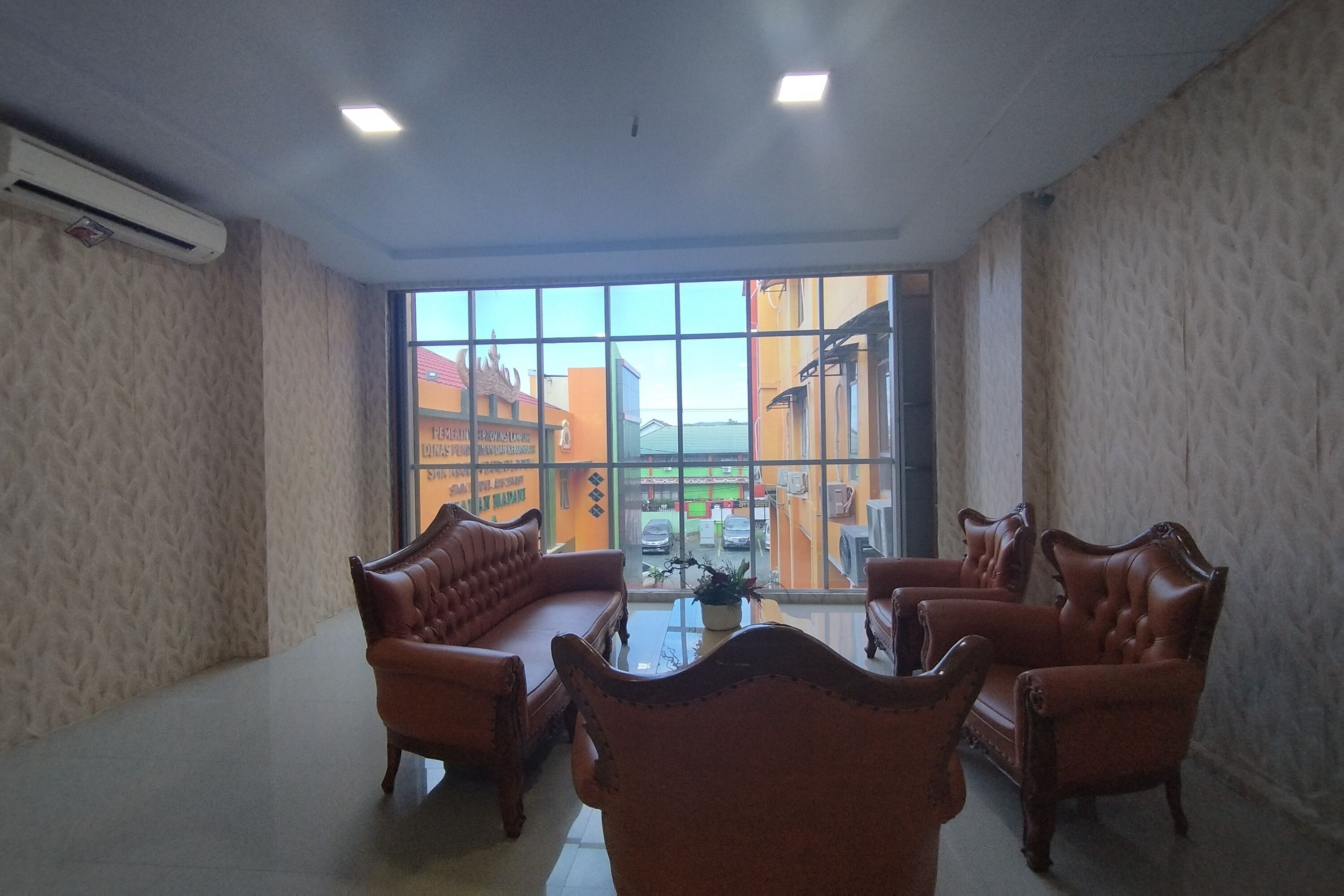 A room with a large window, leather sofas, and a small table with a plant.
